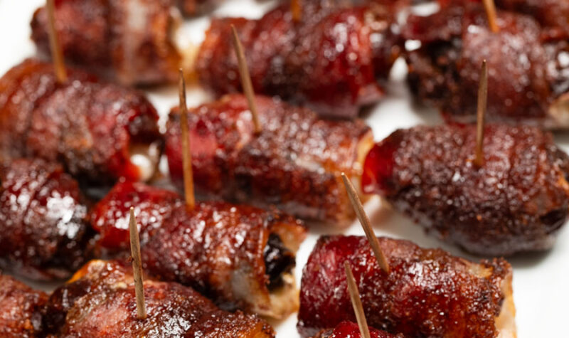 Bacon wrapped dates on a white plate