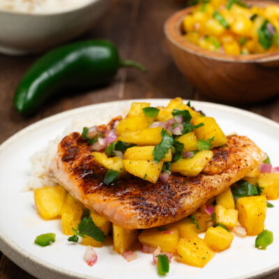 Grilled salmon with pineapple salsa on a white plate
