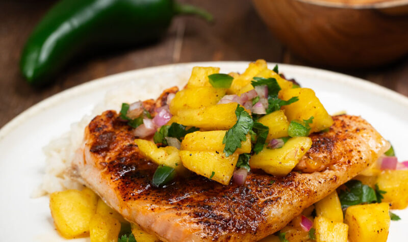 Grilled salmon with pineapple salsa on a white plate