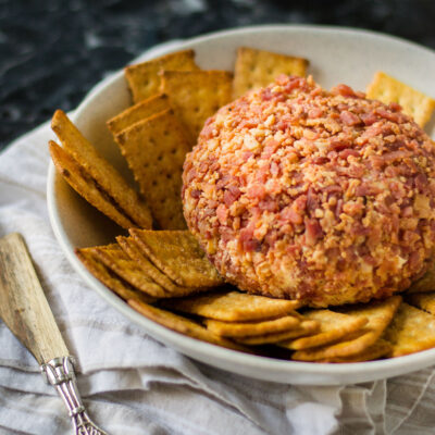 A cheeseball rolled in ham with crackers on the side.