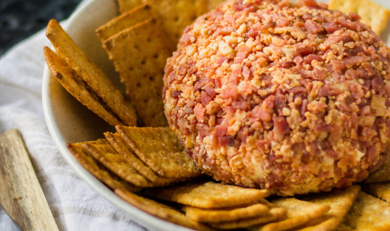 A cheeseball rolled in ham with crackers on the side.