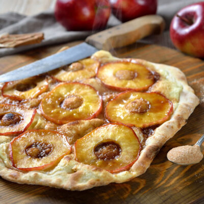 Sliced apples on pizza dough with cinnamon