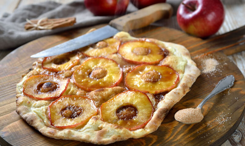Sliced apples on pizza dough with cinnamon