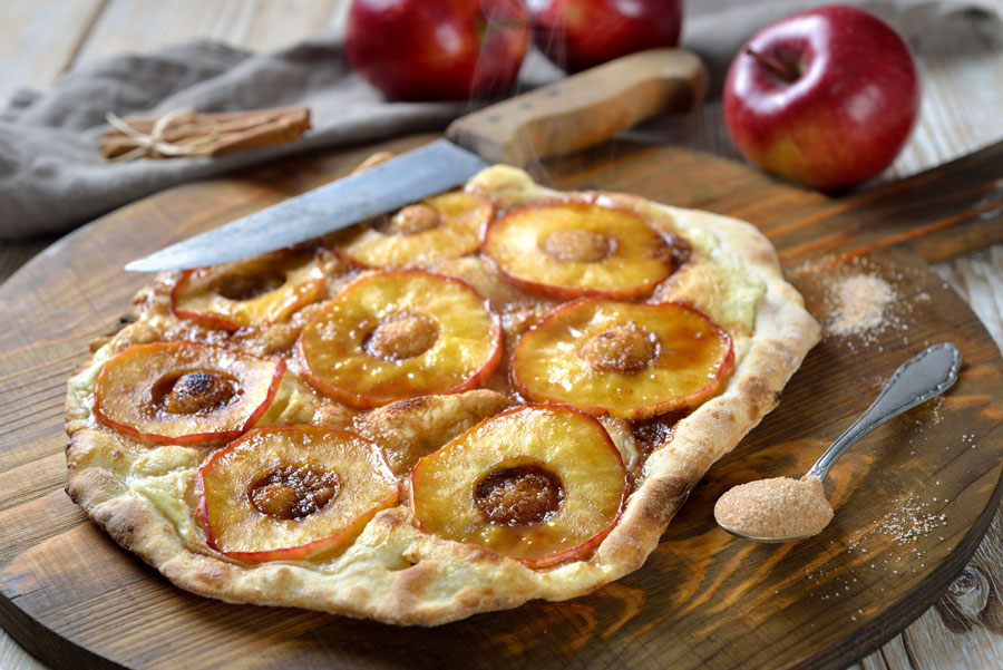 Sliced apples on pizza dough with cinnamon