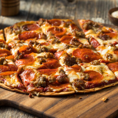 A pepperoni and sausage pizza on parchment paper
