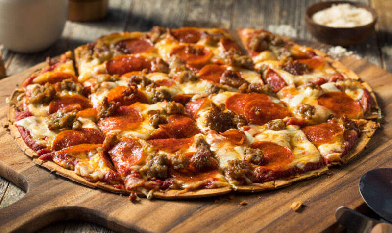 A pepperoni and sausage pizza on parchment paper